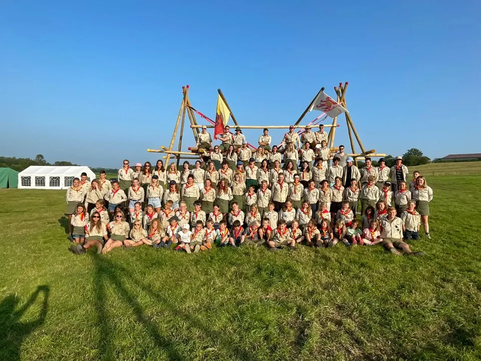 De hele groep van Scouting Rumanzeis op kamp, voor een grote sjorconstructie met onze vlag